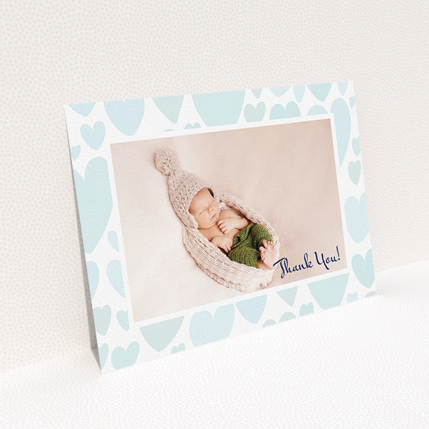 A baby card design named "Pastel Hearts". It is an A5 card in a landscape orientation. It is a photographic baby card with room for 1 photo. "Pastel Hearts" is available as a flat card, with tones of blue and white.
