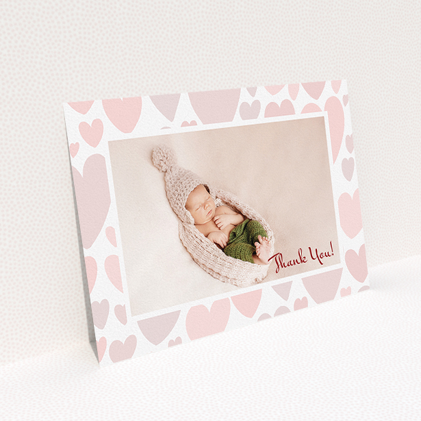A baby thank you card design called "Pastel Hearts". It is an A5 card in a landscape orientation. It is a photographic baby thank you card with room for 1 photo. "Pastel Hearts" is available as a flat card, with tones of pink and white.
