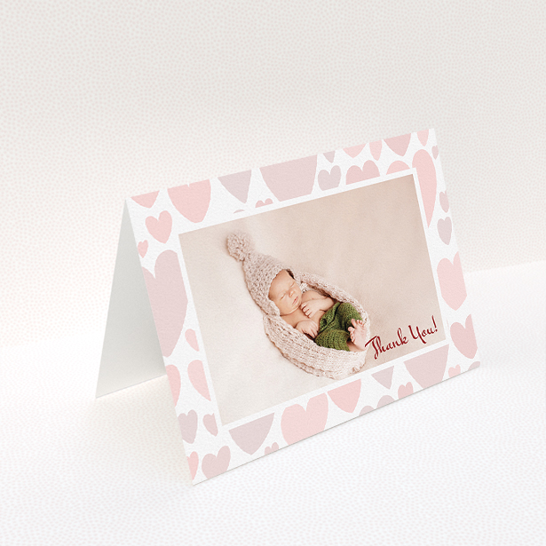 A baby thank you card named "Pastel Hearts". It is an A5 card in a landscape orientation. It is a photographic baby thank you card with room for 1 photo. "Pastel Hearts" is available as a folded card, with tones of pink and white.