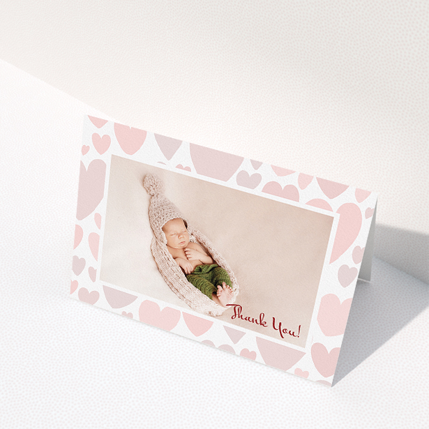 A baby thank you card named "Pastel Hearts". It is an A5 card in a landscape orientation. It is a photographic baby thank you card with room for 1 photo. "Pastel Hearts" is available as a folded card, with tones of pink and white.