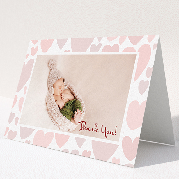 A baby thank you card named "Pastel Hearts". It is an A5 card in a landscape orientation. It is a photographic baby thank you card with room for 1 photo. "Pastel Hearts" is available as a folded card, with tones of pink and white.