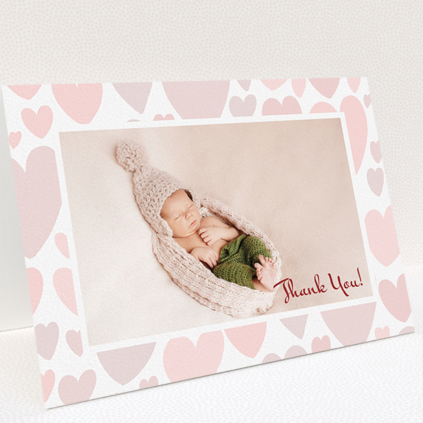 A baby thank you card named "Pastel Hearts". It is an A5 card in a landscape orientation. It is a photographic baby thank you card with room for 1 photo. "Pastel Hearts" is available as a folded card, with tones of pink and white.