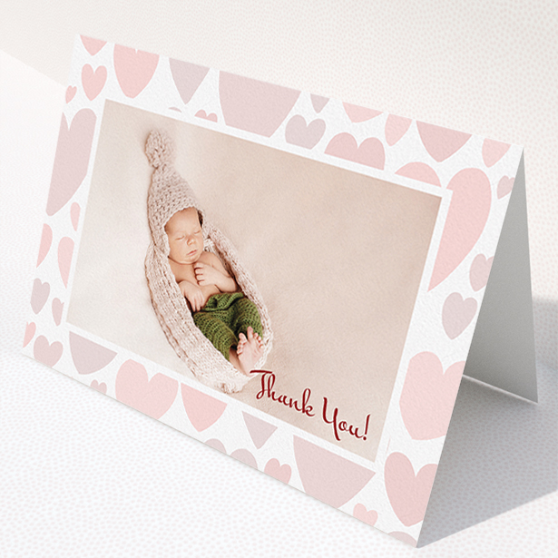 A baby thank you card named "Pastel Hearts". It is an A5 card in a landscape orientation. It is a photographic baby thank you card with room for 1 photo. "Pastel Hearts" is available as a folded card, with tones of pink and white.
