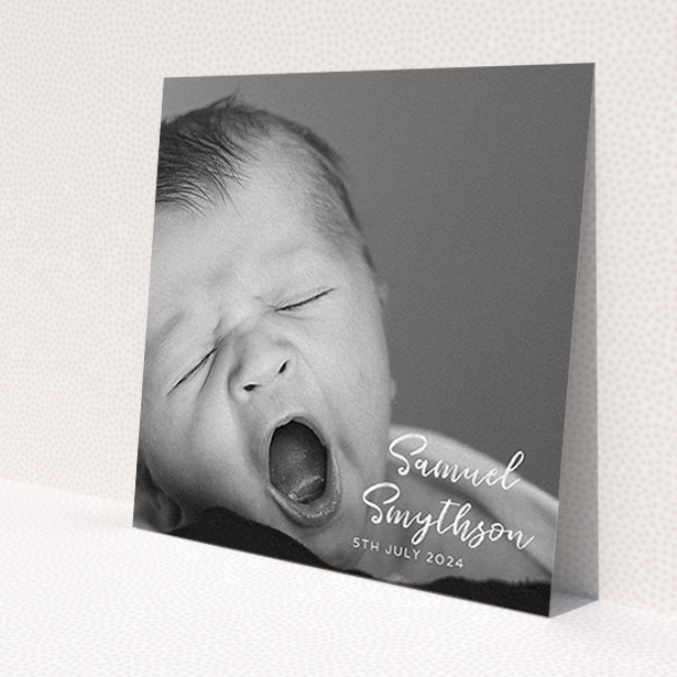 A baptism invitation called 'Soho Script'. It is a square (148mm x 148mm) invite card in a square orientation. It is a photographic baptism invitation with room for 1 photo. 'Soho Script' is available as a flat invite card, with mainly white colouring.