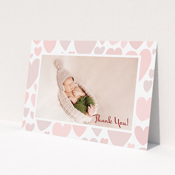 A baptism thank you card design titled 'Pastel Hearts'. It is an A5 card in a landscape orientation. It is a photographic baptism thank you card with room for 1 photo. 'Pastel Hearts' is available as a flat card, with tones of pink and white.