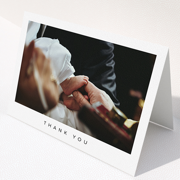 A christening thank you card design named "Simple Thanks". It is an A5 card in a landscape orientation. It is a photographic christening thank you card with room for 1 photo. "Simple Thanks" is available as a folded card, with mainly white colouring.