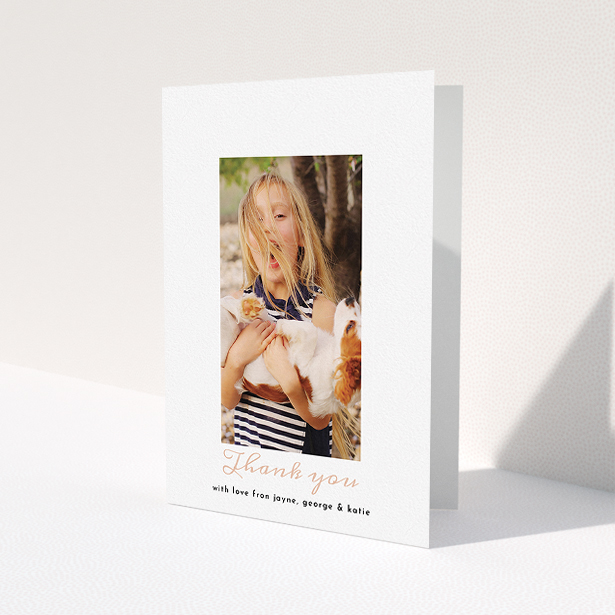 A communion thank you card called 'Central Portrait'. It is an A5 card in a portrait orientation. It is a photographic communion thank you card with room for 1 photo. 'Central Portrait' is available as a folded card, with tones of white and pink.