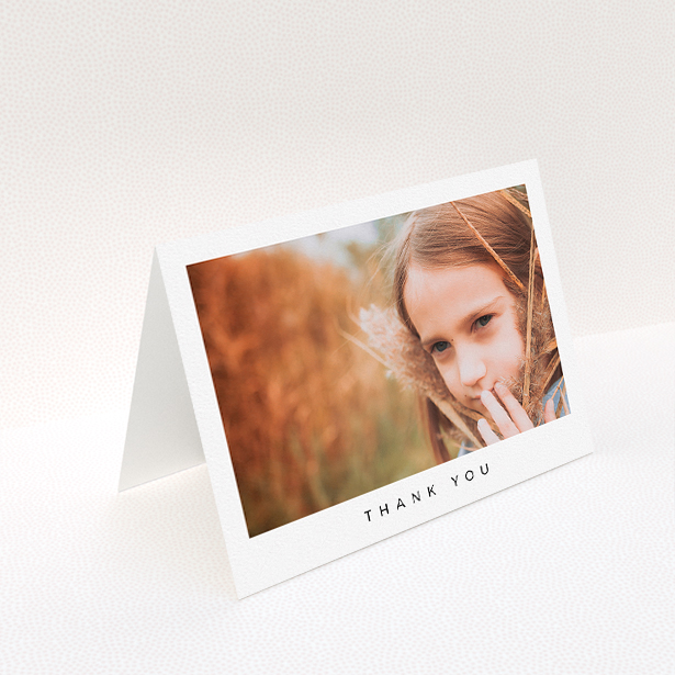 A communion thank you card design titled "Simple Thanks". It is an A5 card in a landscape orientation. It is a photographic communion thank you card with room for 1 photo. "Simple Thanks" is available as a folded card, with mainly white colouring.