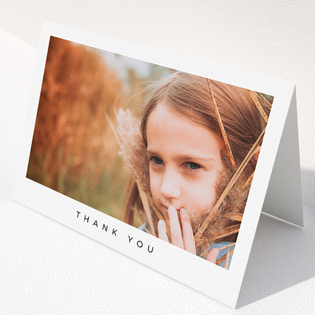 A communion thank you card design titled "Simple Thanks". It is an A5 card in a landscape orientation. It is a photographic communion thank you card with room for 1 photo. "Simple Thanks" is available as a folded card, with mainly white colouring.