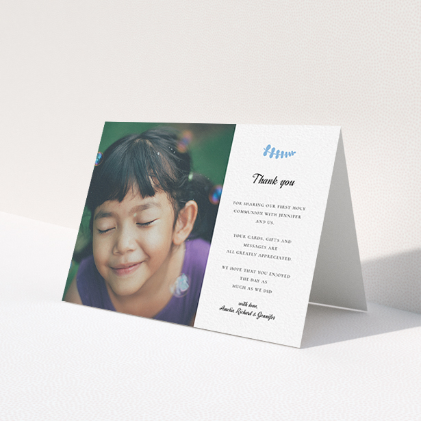 A first holy communion thank you card design called 'Blue Fern'. It is an A6 card in a landscape orientation. It is a photographic first holy communion thank you card with room for 1 photo. 'Blue Fern' is available as a folded card, with tones of white and blue.