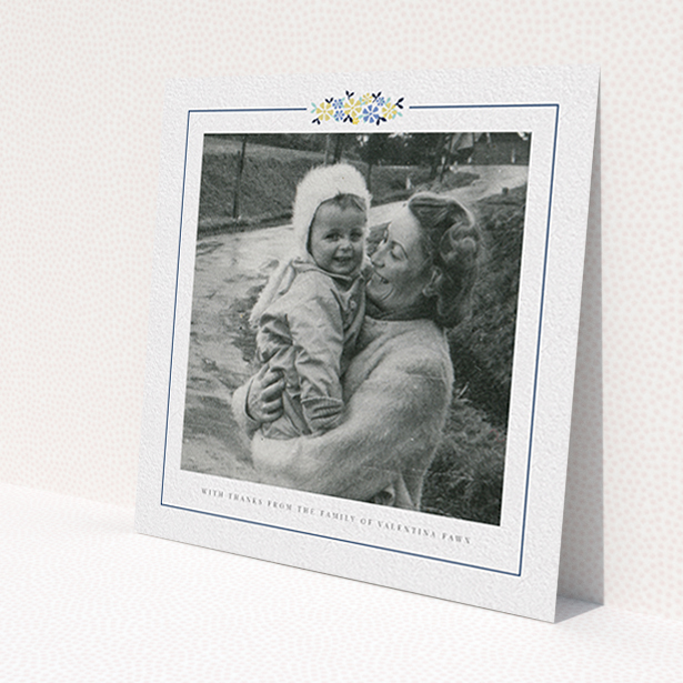 A funeral thank you card template titled 'Remembered in flowers'. It is a square (148mm x 148mm) card in a square orientation. It is a photographic funeral thank you card with room for 1 photo. 'Remembered in flowers' is available as a flat card, with tones of white and blue.