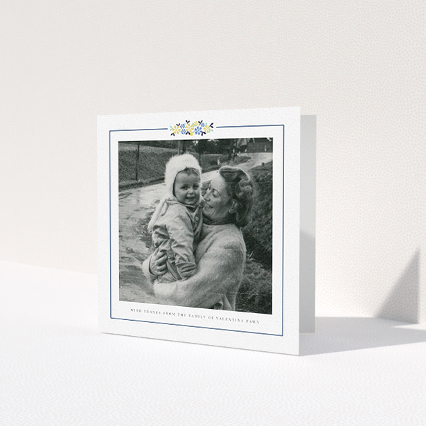 A funeral thank you card design titled 'Remembered in flowers'. It is a square (148mm x 148mm) card in a square orientation. It is a photographic funeral thank you card with room for 1 photo. 'Remembered in flowers' is available as a folded card, with tones of white and blue.