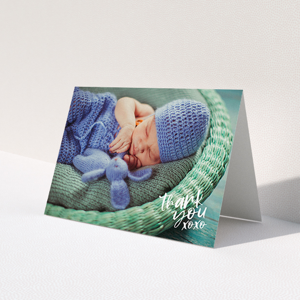 A new baby thank you card template titled 'Thanks In the Corner'. It is an A6 card in a landscape orientation. It is a photographic new baby thank you card with room for 1 photo. 'Thanks In the Corner' is available as a folded card, with mainly white colouring.