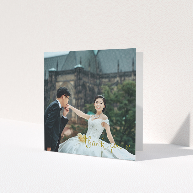 A photo wedding thank you card template titled 'Thank you with a heart'. It is a square (148mm x 148mm) card in a square orientation. It is a photographic photo wedding thank you card with room for 1 photo. 'Thank you with a heart' is available as a folded card, with mainly gold colouring.