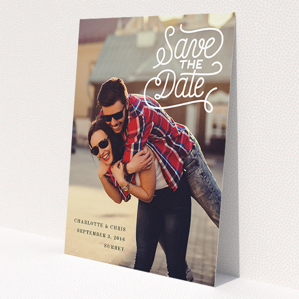 A wedding save the date card design named 'Curly Typography Photo'. It is an A5 card in a portrait orientation. It is a photographic wedding save the date card with room for 1 photo. 'Curly Typography Photo' is available as a flat card, with mainly white colouring.