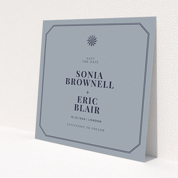 A wedding save the date card called 'Shaded sundial'. It is a square (148mm x 148mm) card in a square orientation. 'Shaded sundial' is available as a flat card, with tones of dark grey and navy blue.