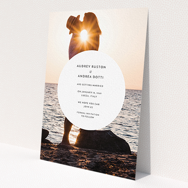 A wedding save the date card template titled 'Surrounded'. It is an A6 card in a portrait orientation. It is a photographic wedding save the date card with room for 1 photo. 'Surrounded' is available as a flat card, with mainly white colouring.