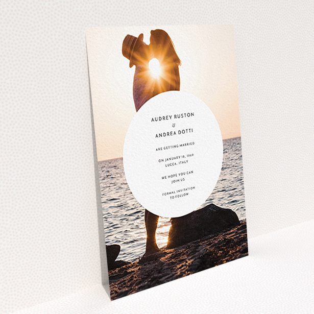 A wedding save the date card template titled "Surrounded". It is an A6 card in a portrait orientation. It is a photographic wedding save the date card with room for 1 photo. "Surrounded" is available as a flat card, with mainly white colouring.