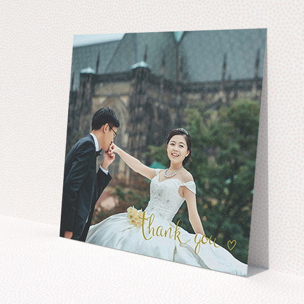 A wedding thank you card named 'Thank you with a heart'. It is a square (148mm x 148mm) card in a square orientation. It is a photographic wedding thank you card with room for 1 photo. 'Thank you with a heart' is available as a flat card, with mainly gold colouring.