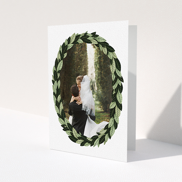 A wedding thank you card named 'Thick Wreath Frame'. It is an A6 card in a portrait orientation. It is a photographic wedding thank you card with room for 1 photo. 'Thick Wreath Frame' is available as a folded card, with tones of light green and dark green.