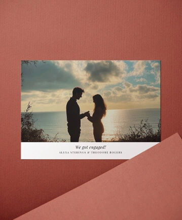 Romantic engagement announcement card featuring a couple silhouetted by a beach sunset