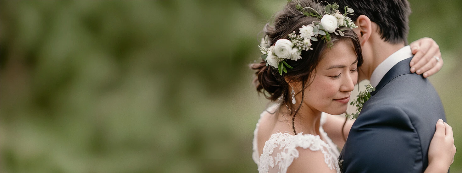 Bride wearing a floral crown hugging her groom, radiating love and elegance in a natural setting