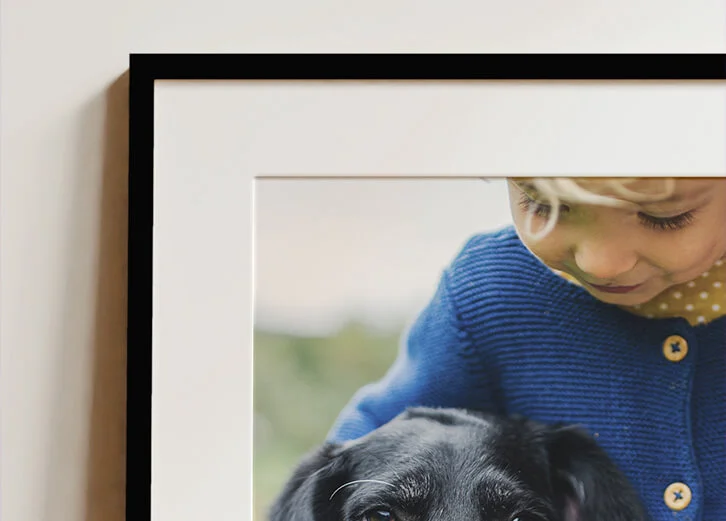 Heartwarming framed and mounted photo of a child and a black dog, ideal for personal gifts or home decor