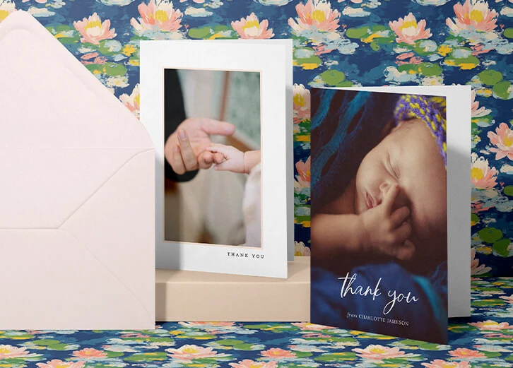 Two beautifully crafted personalised christening thank you cards displayed with matching envelopes against a bold floral background.