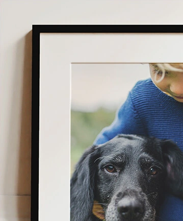 Framed and mounted photo featuring a child and their pet dog in a cosy moment