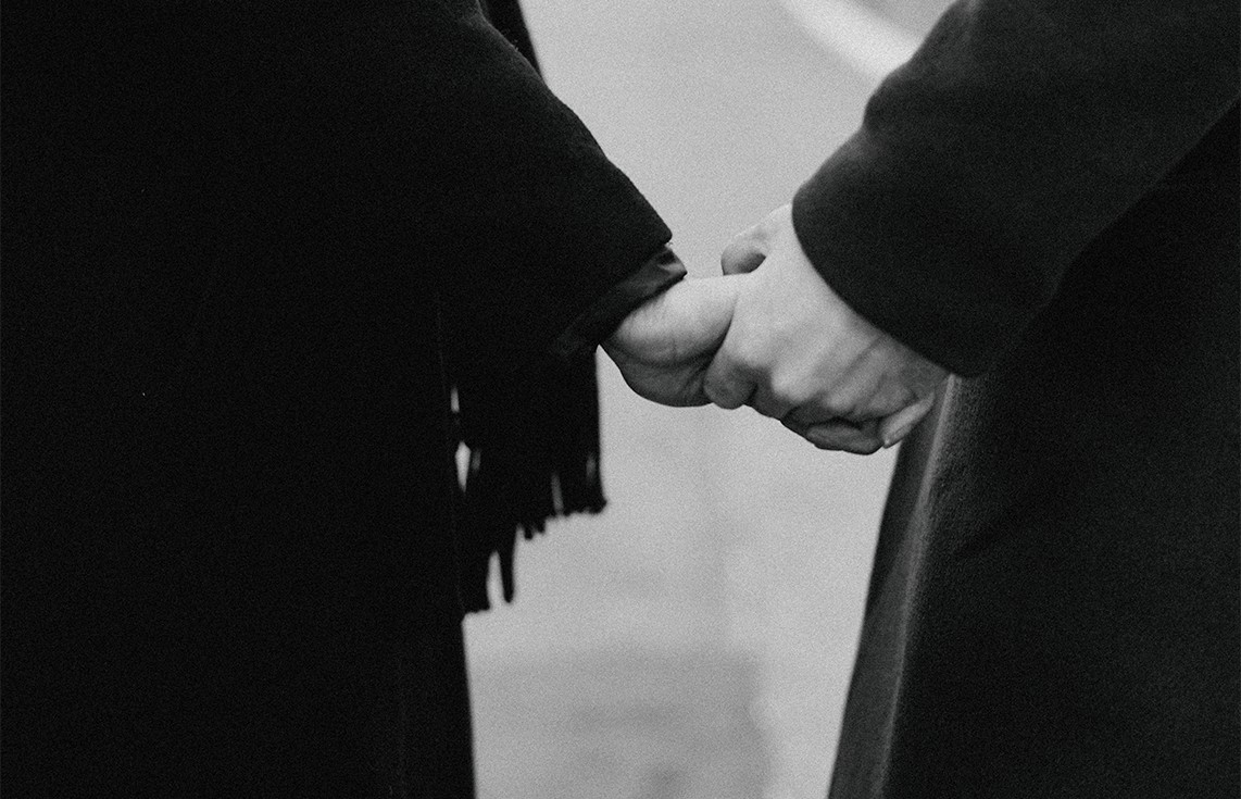 Friends holding hands funeral black white photo