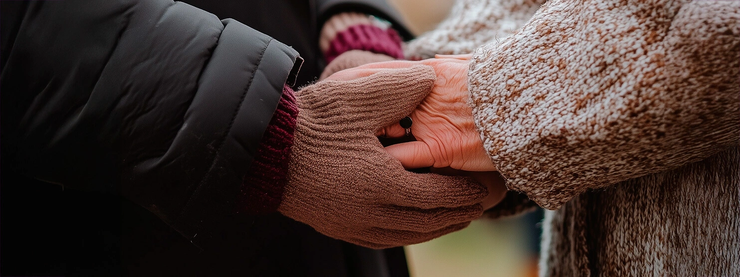 Close-up of two gloved hands holding each other in a comforting gesture