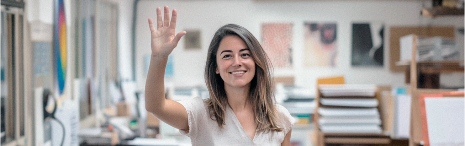 Smiling woman waving in a creative printing studio