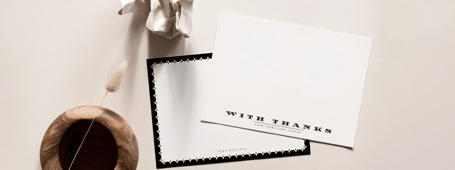 A minimalist thank you card with bold typography and a black scalloped border, displayed with neutral decorative items for an elegant touch.