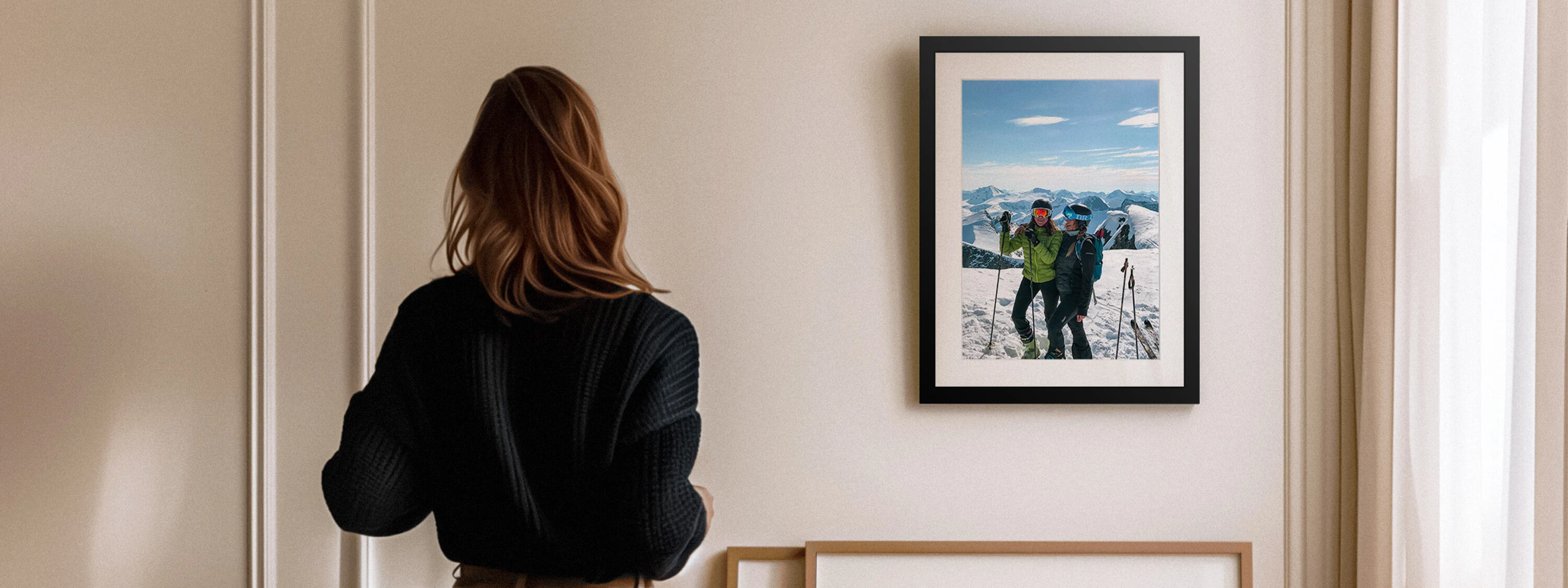 Person admiring a framed winter photo on a wall, showcasing personalised photo décor options like framed prints for seasonal home makeovers.