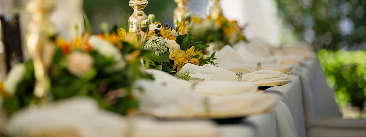 Wedding reception table with elegant floral centrepieces, gold accents, and lush greenery