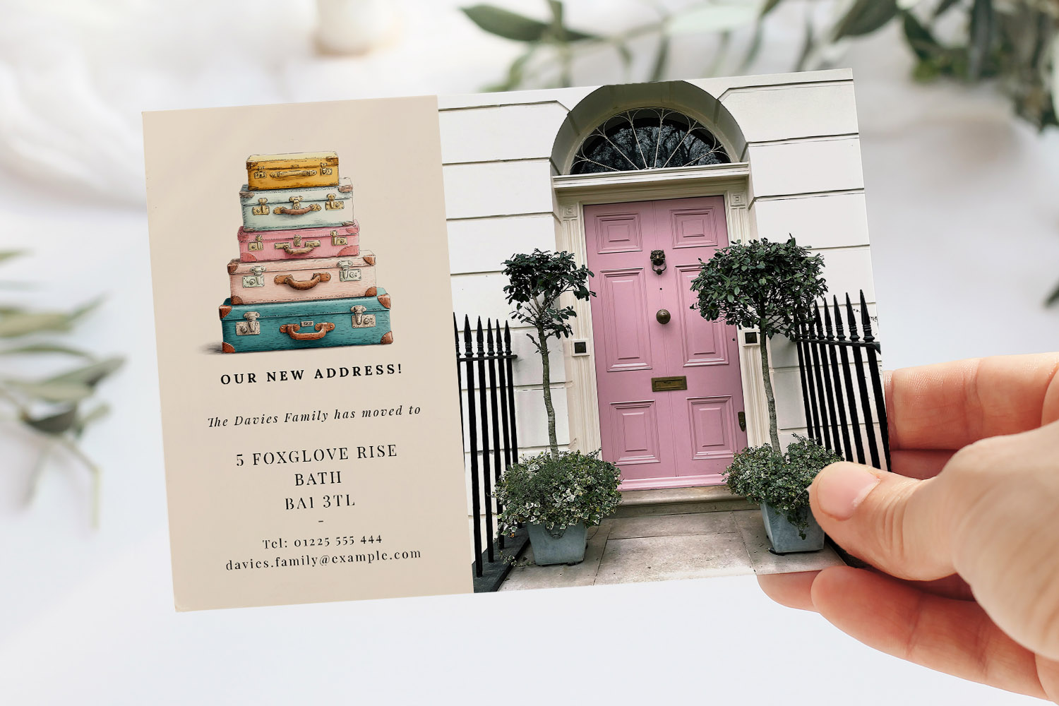 Change of address cards featuring a pastel pink front door and a stack of illustrated vintage suitcases on a cream