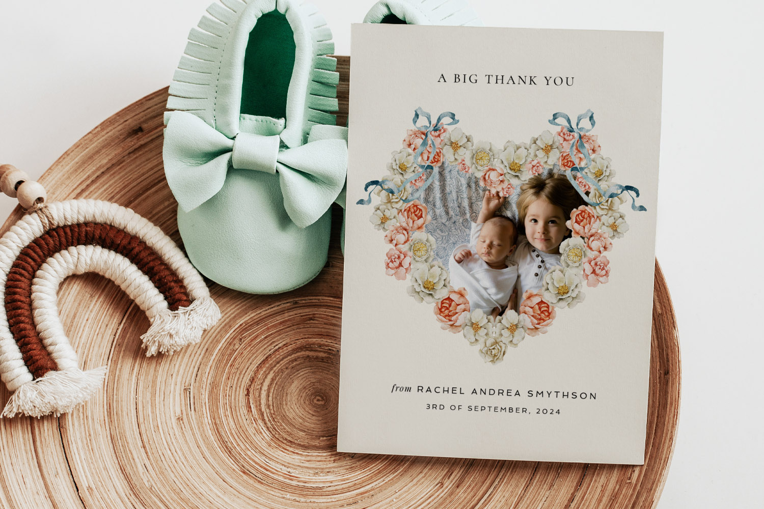 Christening order of service card with floral heart frame and children's photo, displayed beside mint baby shoes and a