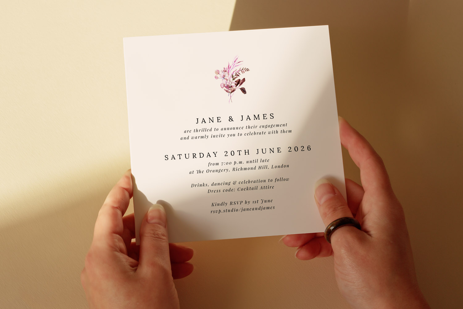 Christening order of service card with minimalist floral design, held in both hands against a soft beige background