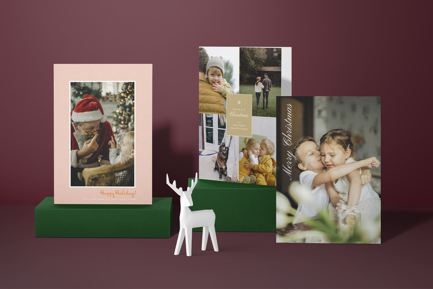 Christmas cards with personalised photo designs displayed on a green stand against a burgundy background with a white