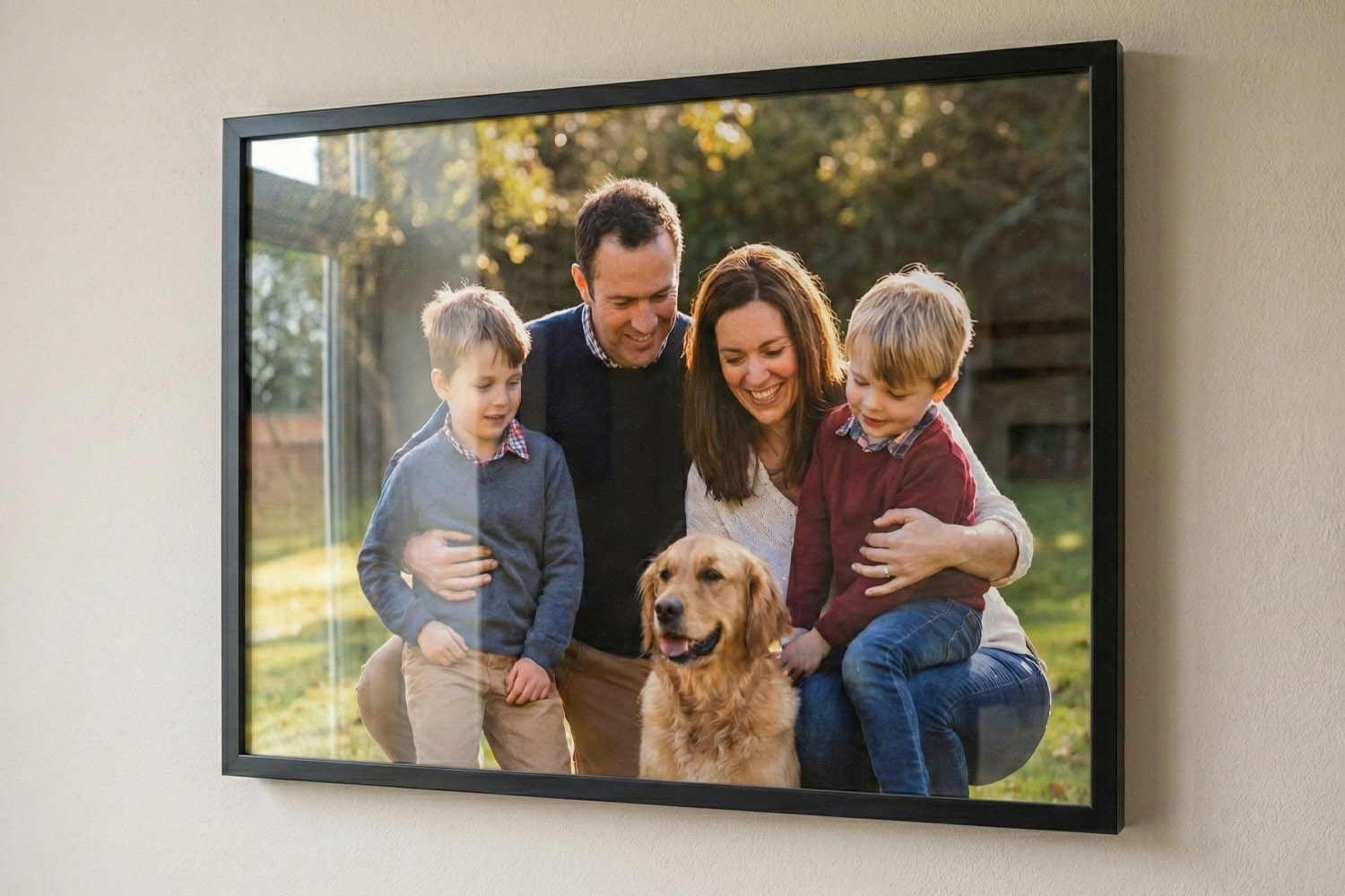 Framed and mounted prints featuring a family and dog, displayed in a sleek black frame on a neutral wall.