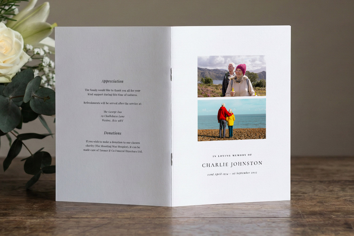 Funeral order of service booklet with personal photos and memorial text, displayed open on a wooden table beside white