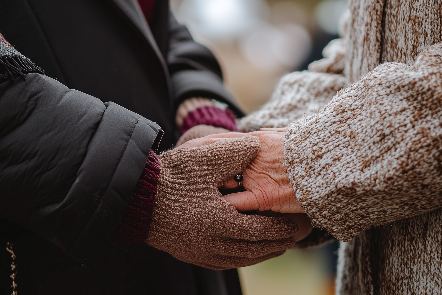 RSVP.studio funerals showing two people holding hands in comfort, one wearing brown gloves and the other a knitted jumper.