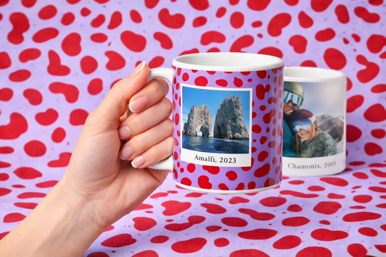 Personalised mugs with custom photo prints and red polka dot design, held in hand against a matching patterned background.