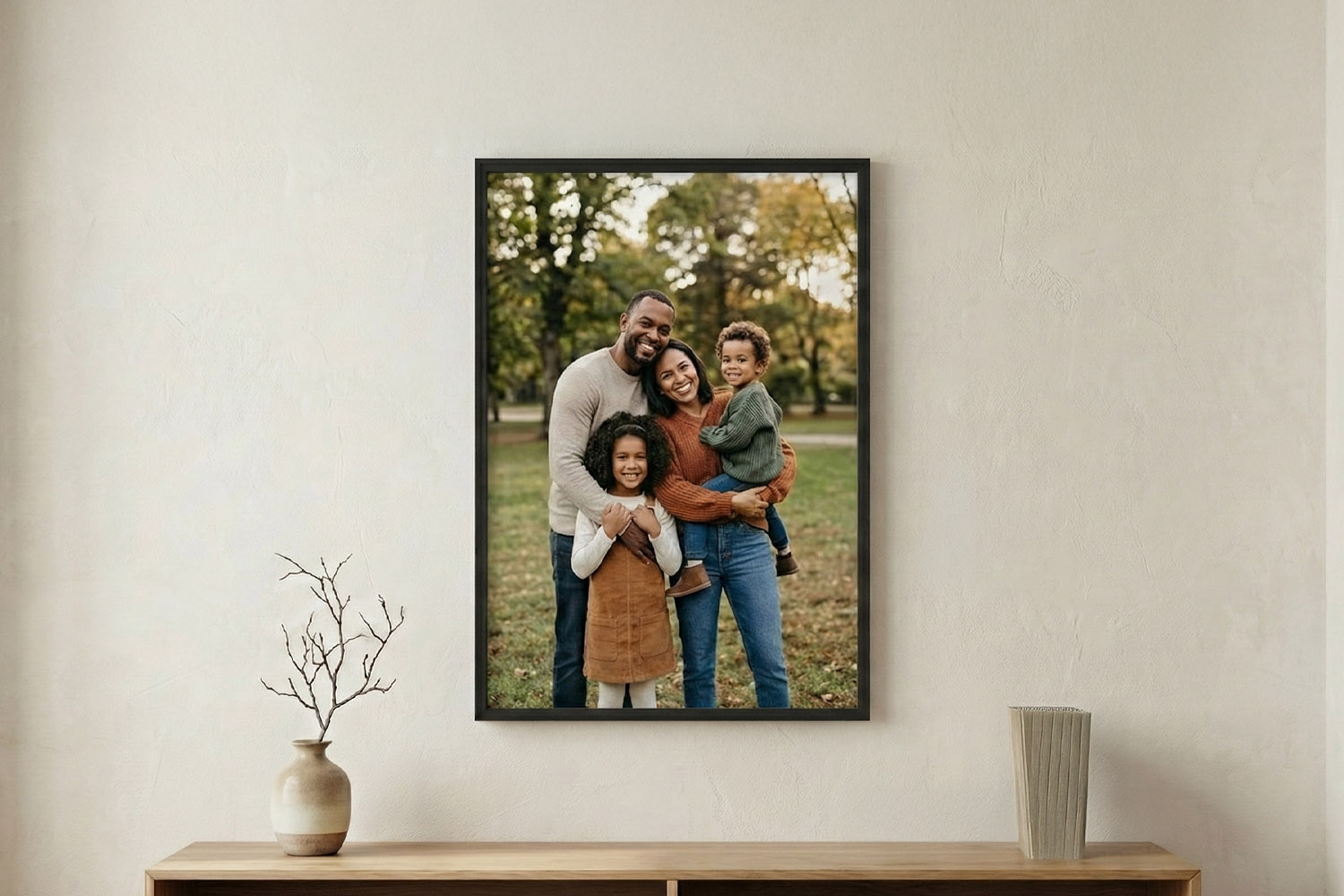 Simple framed prints featuring a family portrait in a black frame, displayed on a neutral wall above a wooden sideboard.