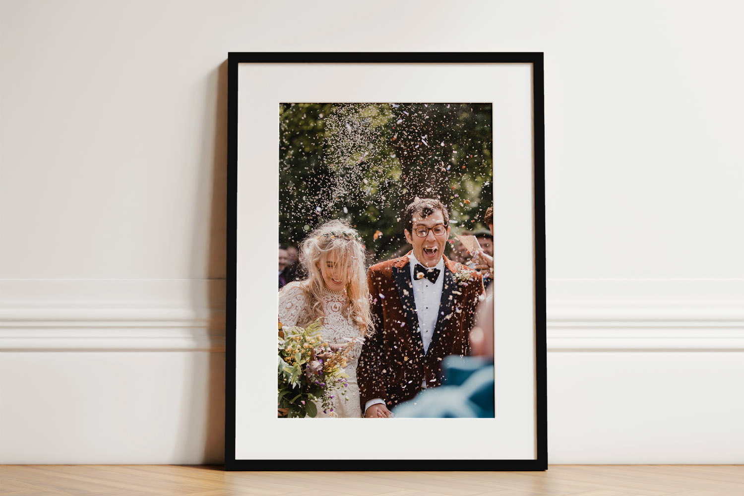 Simple framed prints featuring a wedding photograph in a black frame with white mount, leaning against a white wall.