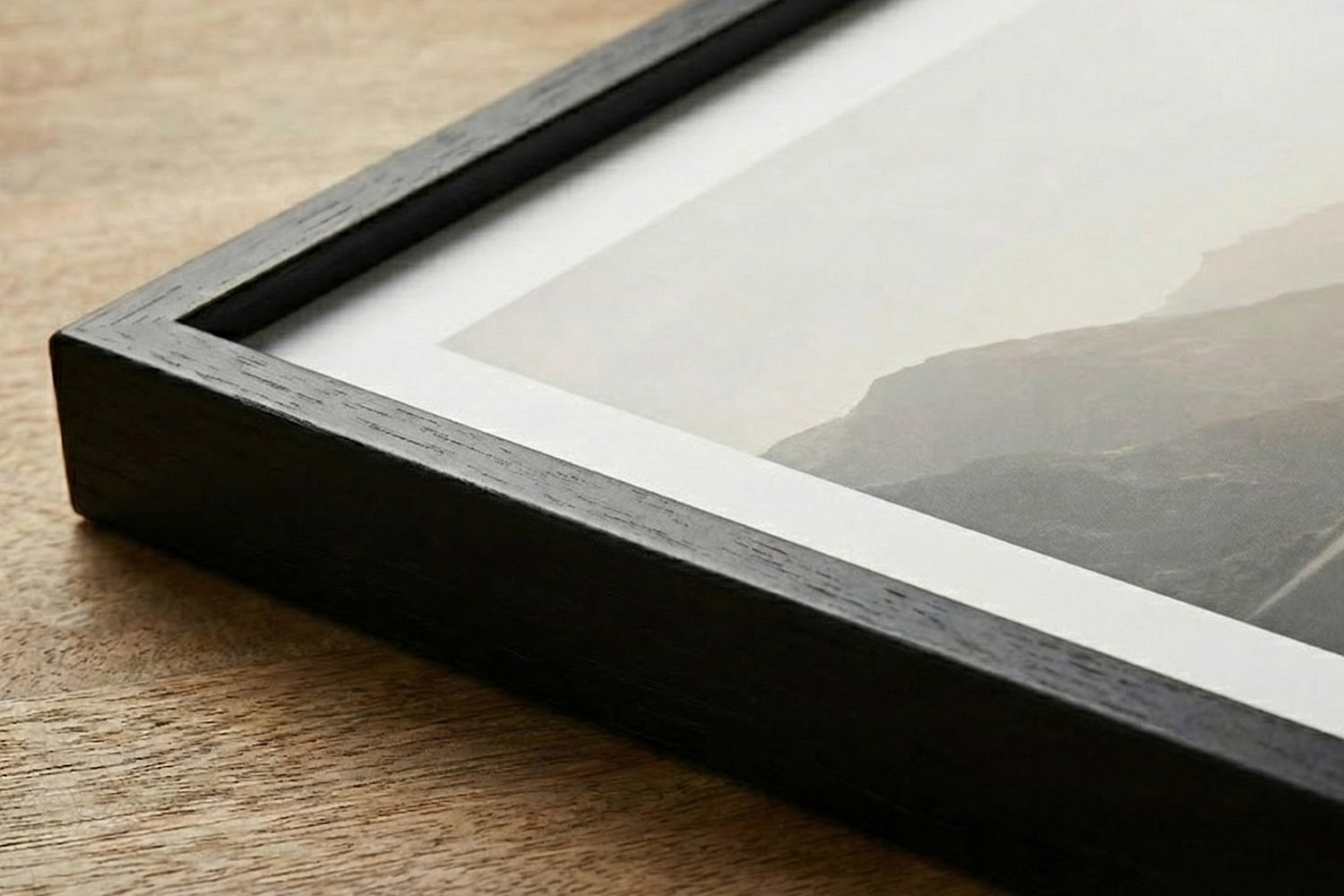 Simple framed prints with a black wooden frame and white mount, displayed on a wooden surface in a close-up view.