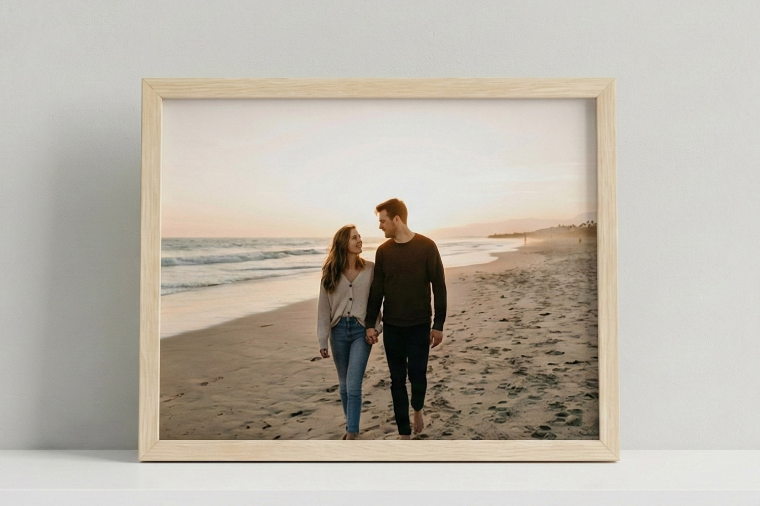 Simple framed prints featuring a couple walking hand in hand on a sandy beach at sunset, displayed in a light wood frame.