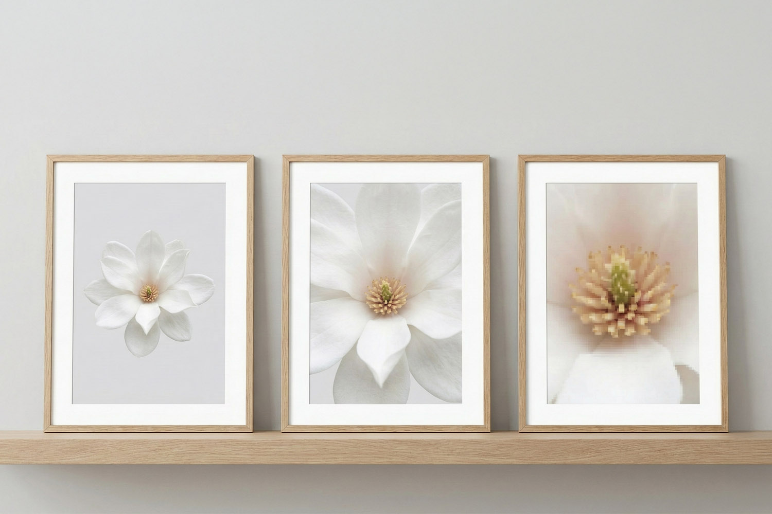 Simple framed prints with minimalist white flower artwork in light wood frames, displayed on a wooden shelf against a grey