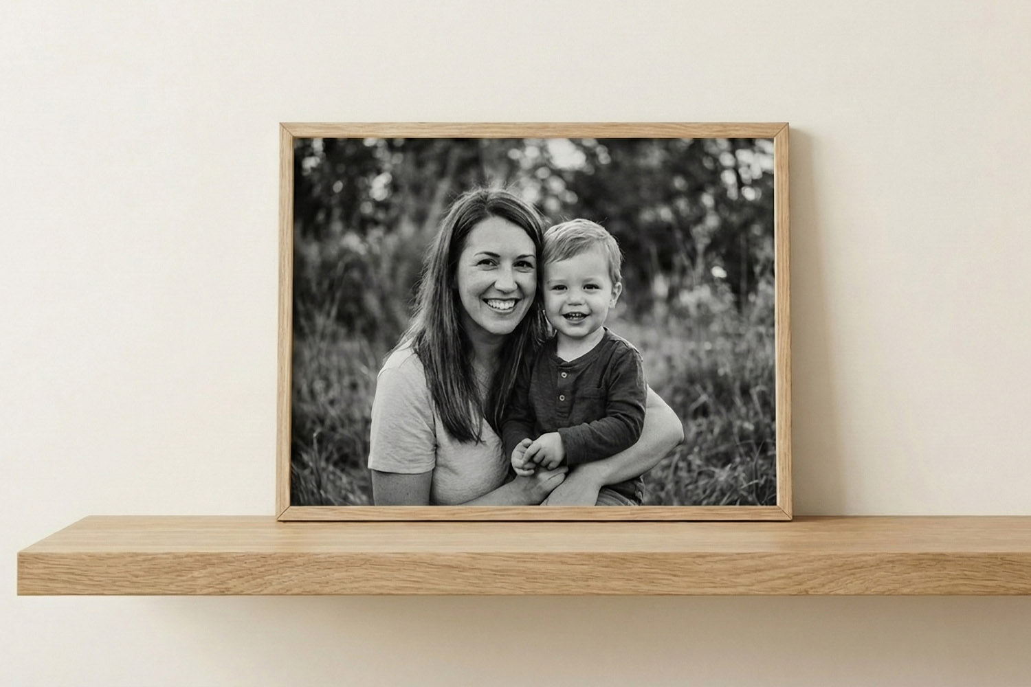 Simple framed prints with a natural wood frame featuring a black and white family portrait on a wooden shelf