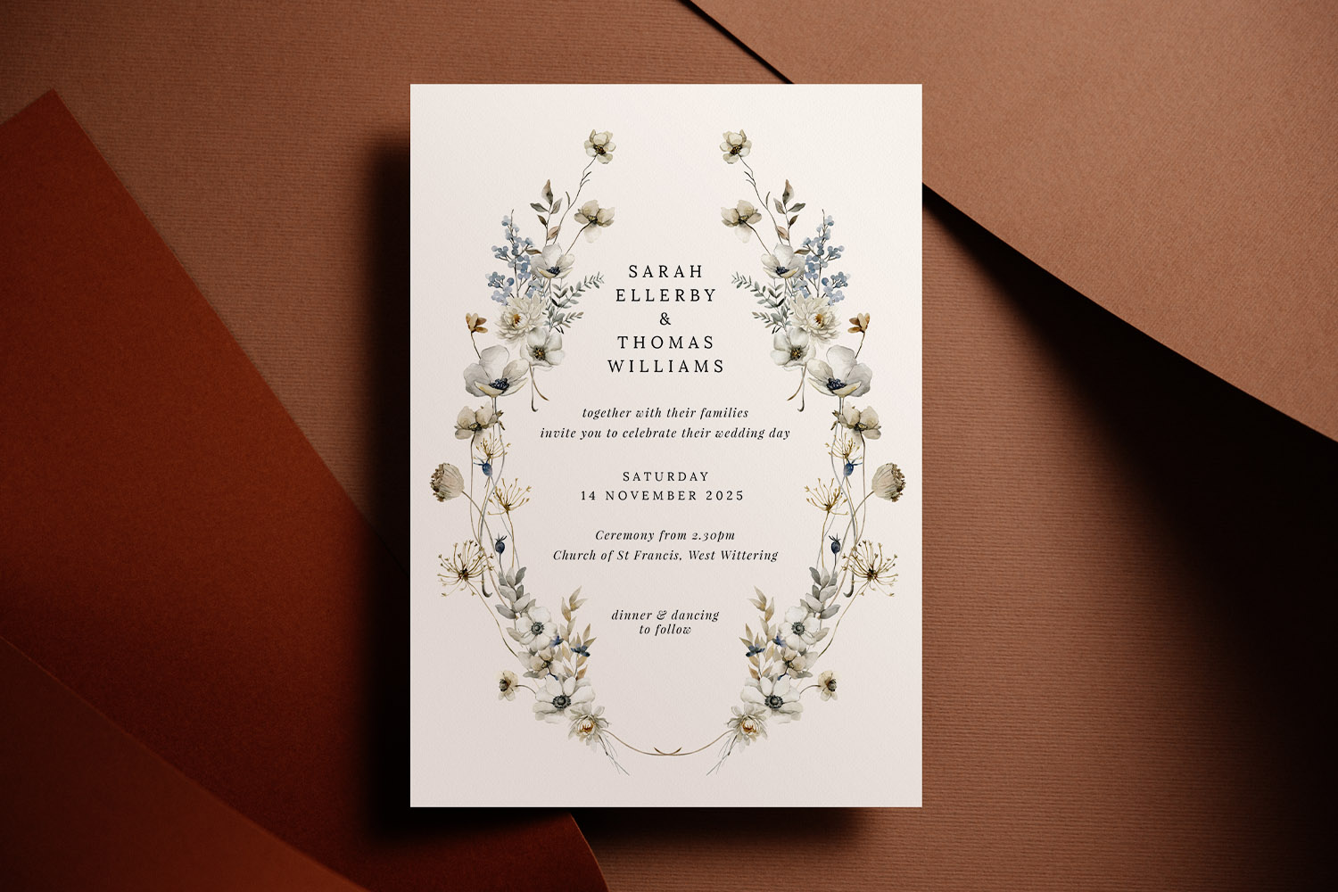 Wedding invitations with elegant floral border and modern typography on cream card, displayed on a brown textured background.
